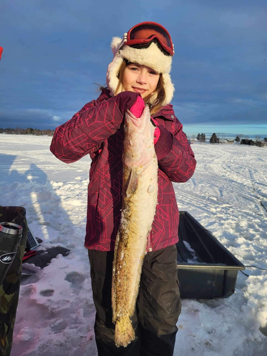 Angler holding a burbot caught during guided ice fishing trip in Maine